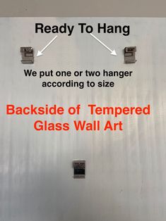 the back side of a glass wall with two hangers attached to it and an arrow pointing