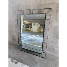 a mirror sitting on the side of a wall next to a parking garage area with no one in it