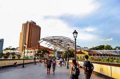 people walking on a bridge in the city with tall buildings and blue sky behind them