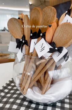 wooden utensils are arranged in a glass bowl on a checkered tablecloth