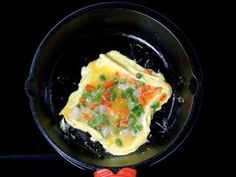 an omelet is cooking in a black skillet