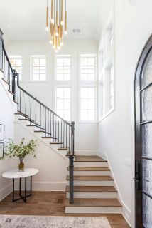 a staircase leading up to a living room with white walls and wood flooring on either side