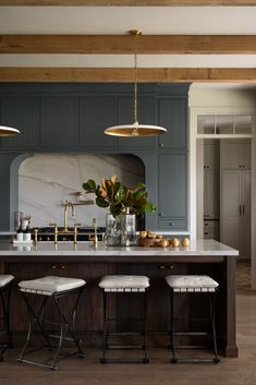 a kitchen with marble counter tops and stools in front of an island topped with plants