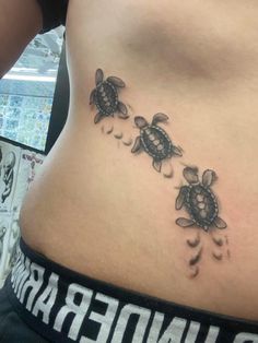 a woman's stomach with two turtle tattoos on her side and under the belly