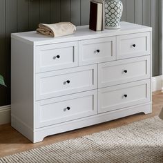 a white dresser with two books and a vase on top