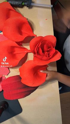 a woman is working on some paper flowers