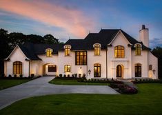 a large white house with lots of windows on it's front lawn at dusk