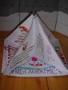 an origami kite with writing on it sitting on top of a wooden floor