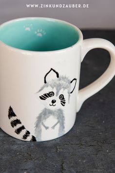 a mug with a drawing of a raccoon on it