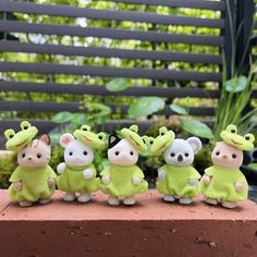 a group of small toy animals sitting on top of a brick wall next to plants