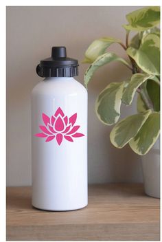 a white water bottle sitting on top of a wooden table next to a potted plant