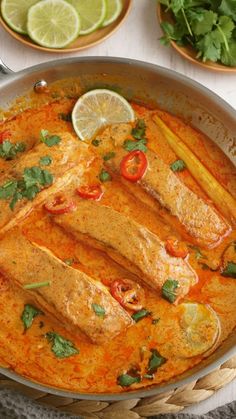 fish in a red curry sauce with limes and cilantro on the side