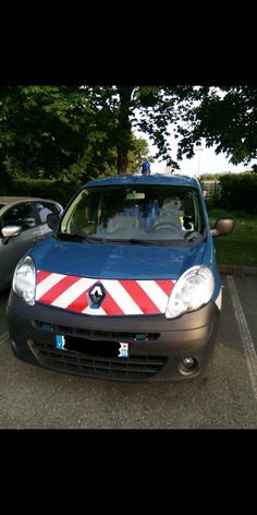 a small blue car with red and white stripes parked in a parking lot next to other cars