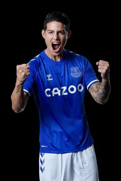 a man in a blue shirt and white shorts with his mouth wide open while standing on a black background