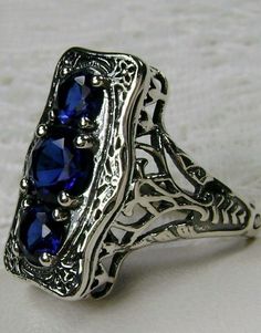 "Simulated Blue Sapphire Ring 3Stone Rectangle#60 Custom Made This is a lovely late Victorian era reproduction ring in solid sterling silver. The gorgeous filigree ring is set with 3 round-cut simulated blue sapphire gemstones. The 2 smaller blue sapphire gems are 4.5mm in diameter, and the center one is 6mm in diameter. This filigree setting is a casting from an actual Antique ring; notice the amazing etched band... The ring sits 3/4th\" (19mm) NS on the finger. The quality of the silver and ge Elegant Multi-stone Rectangular Rings, Elegant Rectangular Multi-stone Rings, Elegant Blue Multi-stone Crystal Ring, Formal Sterling Silver Sapphire Ring With Rectangular Stone, Formal Sapphire Ring With Rectangular Sterling Silver Stone, Blue Three Stone Emerald Cut Jewelry, Formal Rectangular Sapphire Ring In Sterling Silver, Blue Emerald-cut Three-stone Jewelry, Blue Emerald Cut Three Stone Jewelry