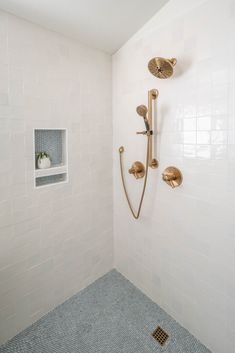 a bathroom with white tile and gold shower faucet next to blue tiled floor