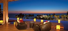 two wicker chairs sitting on top of a wooden deck next to a swimming pool