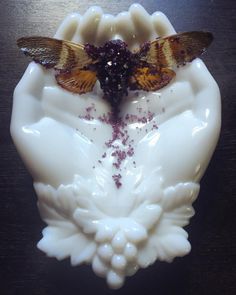 two butterflies sitting on top of a piece of white art glass with red and yellow sprinkles