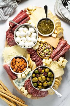 an assortment of cheeses, meats and nuts on a platter with breadsticks