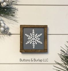 a snowflake is mounted on the wall next to christmas tree branches and balls