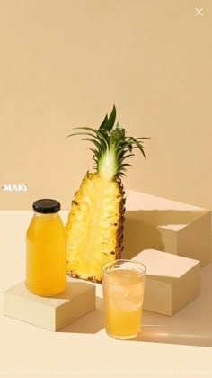 a pineapple sitting next to two jars of juice on top of a white table