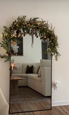 a living room with a couch and christmas decorations on the wall in front of a mirror