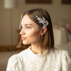 a woman with a veil on her head wearing a white dress and hair combs