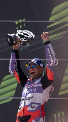 a man is holding his helmet up in the air while wearing a colorful shirt and sunglasses