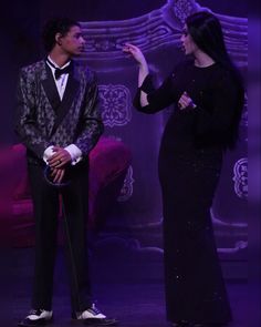 a man in a tuxedo standing next to a woman wearing a black dress