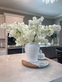 a white vase filled with flowers sitting on top of a kitchen counter next to an oven