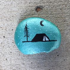 a painted rock with a tent and trees on it