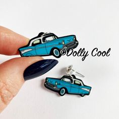 a pair of blue car shaped earrings on top of a white background with the words dory cool