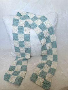 a crocheted scarf sitting on top of a pillow