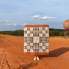 a person standing in the middle of a dirt road with a blanket on their back