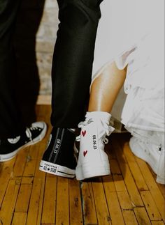 two people standing next to each other on top of a wooden floor with their feet in the air