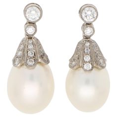 A beautiful pair of white cultured pearl and diamond drop earrings set in 18k white gold. Each earring is firstly composed of a rub over round brilliant cut diamond stud, secured to reverse with a post and butterfly fitting. Hanging freely from the stud is a diamond set floral cap which encases a 10-millimetre white cultured pearl. The contrast of the sparkly diamonds against the lustrous pearl is a classic pairing and looks extremely elegant once on the ear. Due to their design and style the ea Classic White Gold Pearl Earrings, Classic Formal Pierced Diamond Earrings, Classic Platinum Pear-shaped Diamond Earrings, Classic Formal Diamond Pierced Earrings, Classic Platinum Pearl Earrings For Formal Occasions, Classic Silver Platinum Pearl Earrings, White Gold Pearl Drop Pear-shaped Earrings, White Gold Pearl Drop Earrings In Pear Shape, White Diamond Pierced Earrings For Formal Occasions