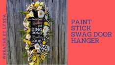 a door hanger decorated with flowers and saying paint stick swag door hanger