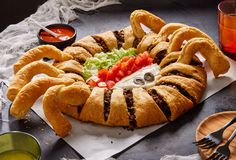 a crab shaped bread dish with vegetables and sauces on the side next to it