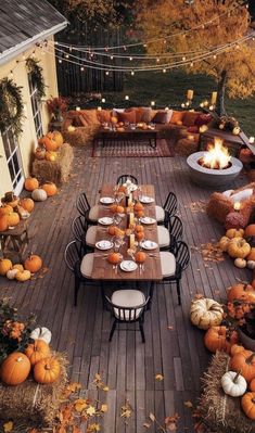 an outdoor dining area is decorated with pumpkins, hay bales and string lights