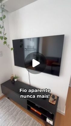 a flat screen tv mounted to the side of a wall next to a plant in a living room