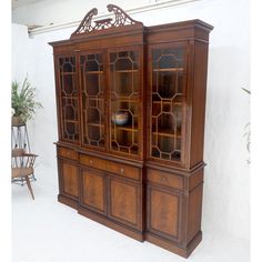 an old wooden china cabinet with glass doors on the top and bottom, in front of a white wall