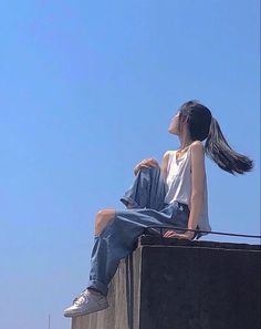 a woman sitting on top of a cement wall