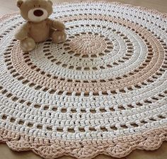 a teddy bear sitting on top of a crocheted rug