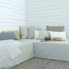 a white couch sitting on top of a wooden floor next to pillows and rugs