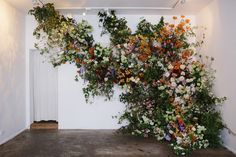 an arrangement of flowers is displayed on the wall