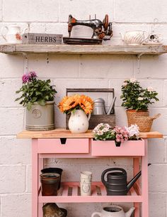 a pink shelf with flowers and watering cans on it