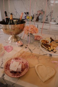 a table topped with plates filled with food next to bottles of champagne and wine glasses