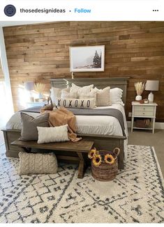 a bed with pillows and blankets on top of it in front of a wooden wall