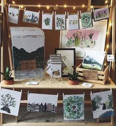 an assortment of cards and pictures are displayed on a table with string lights strung around them