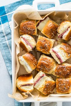 a pan filled with mini sandwiches on top of a blue and white table cloth next to a